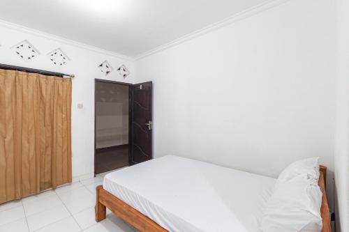 a white bedroom with a bed and a closet at OYO Life 93504 Kost Krisna in Temukus