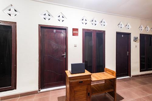 a room with three doors and a desk with a laptop at OYO Life 93504 Kost Krisna in Temukus