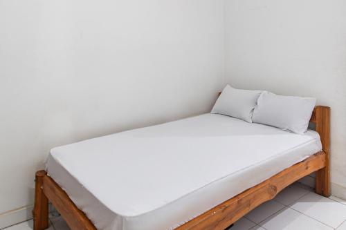 a bed with white sheets and two pillows on it at OYO Life 93504 Kost Krisna in Temukus