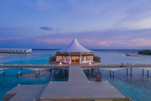 a building on a dock in the water at Cinnamon Hakuraa Huraa Maldives - All Inclusive in Meemu Atoll