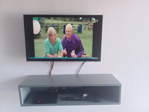 a television with two older men on the screen at Exclusive-View Lodge in Akropong