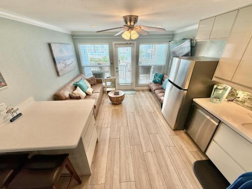a kitchen with a refrigerator and a living room at Seascape 2202 The Seashell Pearl Beachfront Condo Gulf Views Pool Hottubs Netflx in Galveston