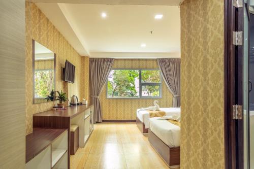 a hotel room with two beds and a desk at Jomtien Sands Residence in Jomtien Beach