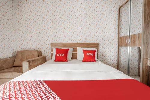 a bedroom with a bed with two red pillows at Hotel O Tamansari Panoramic Apartment By Anwar in Bandung