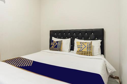 ein Bett mit blau-weißen Laken und Kissen in der Unterkunft Hotel O Triple N Homestay in Sidoarjo
