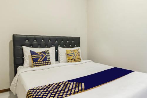 ein Bett mit blauen und gelben Kissen darauf in der Unterkunft Hotel O Triple N Homestay in Sidoarjo