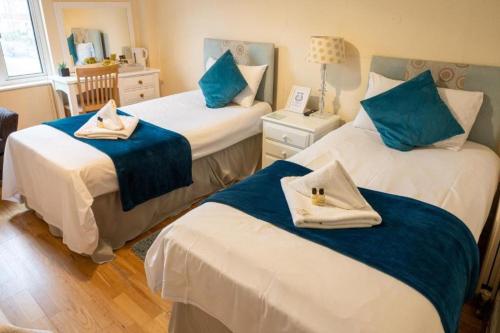 a bedroom with two beds with blue and white sheets at OYO Lina Guest House in Oxford