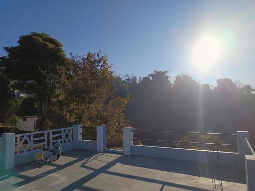 a white fence with the sun in the sky at Dwarahat Village Farmstay- Babaji's Cave in Dwārāhāt