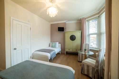 a bedroom with two beds and a table and a window at OYO Lina Guest House in Oxford
