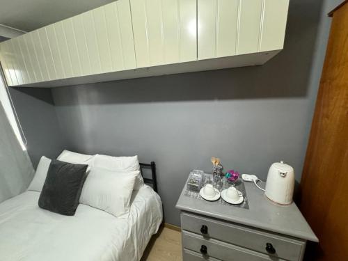 a bedroom with a bed and a dresser with cups and a cabinet at Brazilian Family in Uk 02 in Oxford