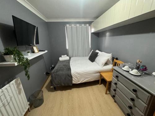 a small bedroom with a bed and a dresser with a television at Brazilian Family in Uk 02 in Oxford
