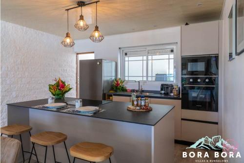 a kitchen with a counter and some stools in it at Matira Beach House in Bora Bora