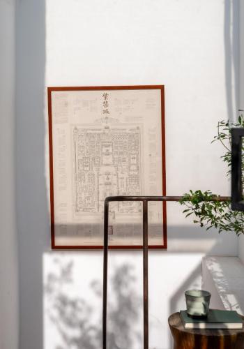 a framed document on a wall next to a table at Beijing Le Zai Nan Luo Gu Xiang Wang Fu Jing Forbidden City Courtyard Hotel&Free laundry service&Free coffee &Paid Dumpling experience service in Beijing