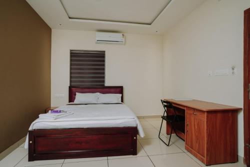 a bedroom with a bed and a desk in it at Atland Residency in Calicut