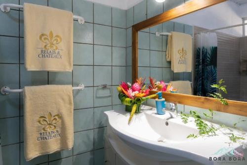 Un baño con lavabo, espejo y toallas. en Iihi House, en Bora Bora