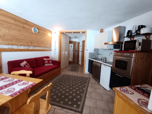Il comprend une cuisine et un salon avec un canapé rouge. dans l'établissement Résidence Ferme D'augustin - Batiment F - Superbe appartement pieds des pistes avec terrasse MAE-6121, à Montgenèvre