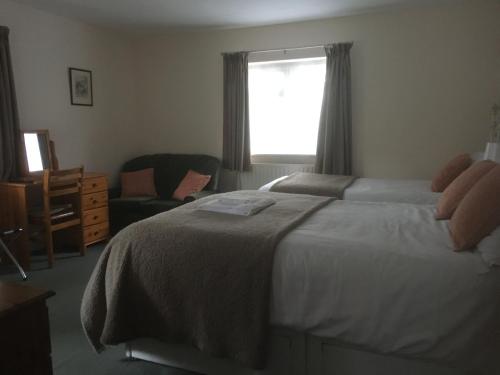 a bedroom with a bed and a chair and a window at Grove House Guest House in Telford