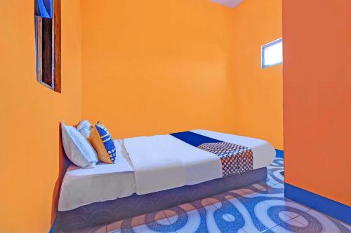 a bed in a room with an orange wall at Hotel O Wisma Dua Putra Syariah in Majalengka