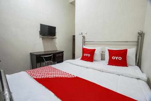a red and white bed with two red pillows at Hotel O Hidayah Homestay Syariah in Sidoarjo