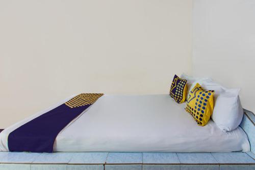 una cama con almohadas coloridas encima en Hotel O Losmen Ida Near PT. Narmada Awet Muda (Pabrik Lingsar), en Lembuak