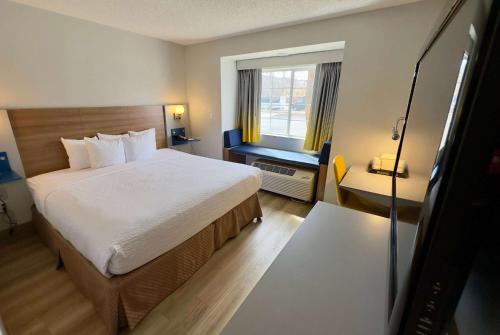 a hotel room with a bed and a window at Microtel Inn & Suites by Wyndham Denver Airport in Denver