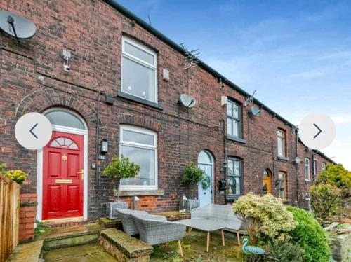 a brick house with a red door and a patio at Duck Cottage beautiful views countryside village in Delph