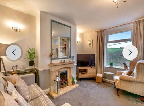 a living room with a fireplace and a large window at Duck Cottage beautiful views countryside village in Delph
