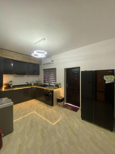 a large kitchen with black cabinets and appliances in it at AJ's Exclusive Apartment in Abuja