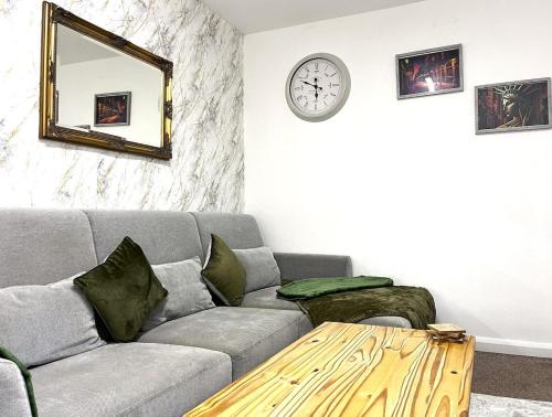 a living room with a couch and a clock on the wall at Cosy Flat 6 People, Short Drive - NEC-Airport-Birmingham-Solihull in Birmingham