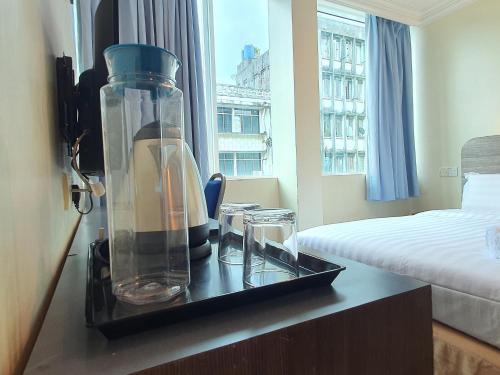 a room with a bed and a glass jar on a table at Capital O 90939 Sandakan Central Hotel in Sandakan