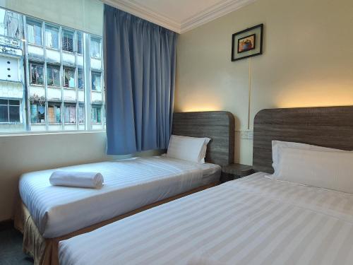 a hotel room with two beds and a window at Capital O 90939 Sandakan Central Hotel in Sandakan