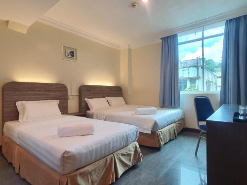 a hotel room with two beds and a window at Capital O 90939 Sandakan Central Hotel in Sandakan