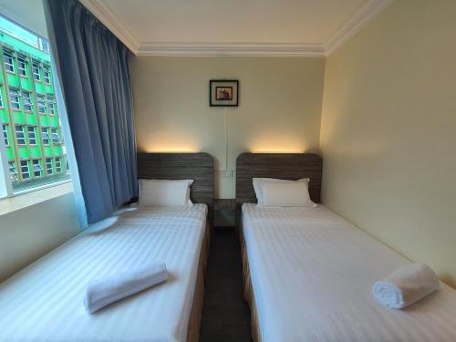 two twin beds in a room with a window at Capital O 90939 Sandakan Central Hotel in Sandakan