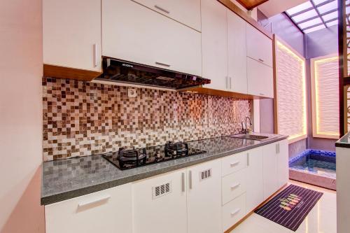 a kitchen with white cabinets and a tile wall at Capital O 93718 Homestay 3 Bidadari in Yogyakarta