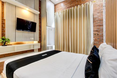 a bedroom with a bed and a tv and a brick wall at Capital O 93718 Homestay 3 Bidadari in Yogyakarta