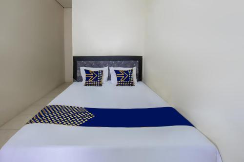 un lit avec des draps et des oreillers bleus et blancs dans l'établissement SPOT ON 93724 Songgong Homestay, à Kuta Lombok