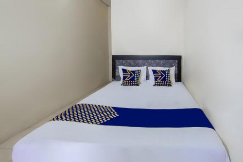un lit avec des draps et des oreillers bleus et blancs dans l'établissement SPOT ON 93724 Songgong Homestay, à Kuta Lombok