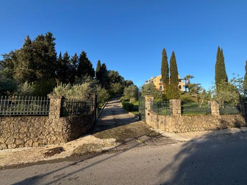 a stone fence next to a road with trees at Athinas House in Corfu Town