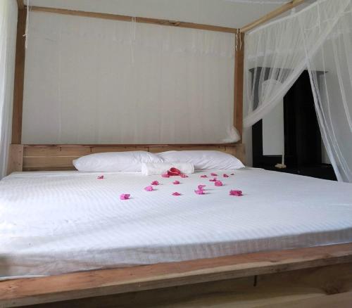 a bed with pink rose petals on it at Milk House Mirissa, Entire Home, Authentic Village in Mirissa