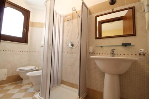 a bathroom with a sink and a toilet and a mirror at Zingaro Hotel in San Vito lo Capo