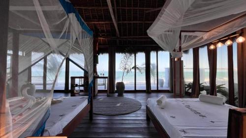 a bedroom with two beds and a view of the ocean at Tikipalmbeachhotel in Paje