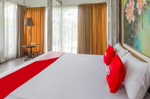 a bedroom with a large white bed with red pillows at Hotel O Tungku Klui Hotel in Mangsit