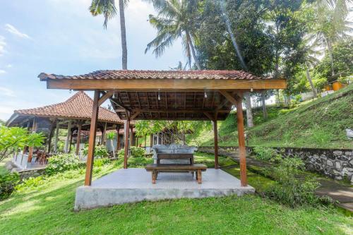 a wooden pavilion with a bench in the grass at Hotel O Tungku Klui Hotel in Mangsit