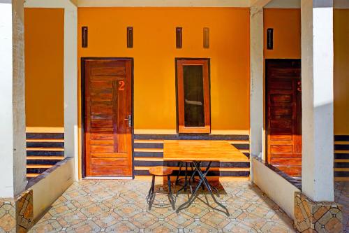 un tavolo e una sedia davanti a un muro arancione di Hotel O Sejolie Sibayak a Berastagi