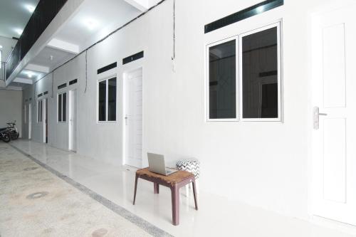 a hallway with white walls and a laptop on a bench at Hotel O 45 Guest House in Sragen