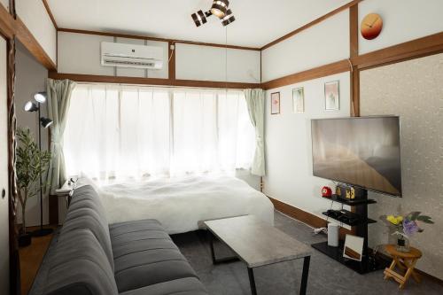 a bedroom with a bed and a couch and a tv at 金運の上がる宿 岡山駅徒歩圏内 駐車場無料 最大6名 完全貸切 in Okayama