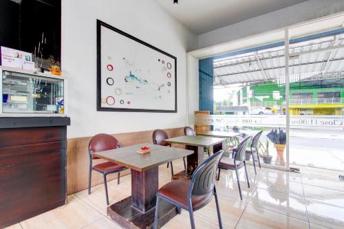 a restaurant with tables and chairs and a large window at Hotel O Wonosobo Bunkbed in Wonosobo