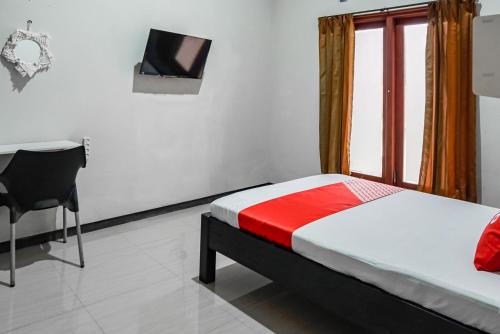 a bedroom with a bed and a desk and a television at Hotel O Regina Homestay Syariah in Surabaya