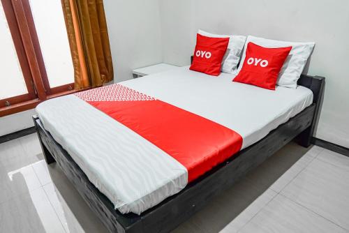 a bed in a room with red pillows on it at Hotel O Regina Homestay Syariah in Surabaya