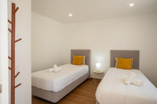 two beds in a room with white and orange pillows at Seaing House II in Falca